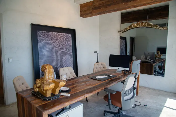 Sala de consulta do Dr. Guilhermino, com mesa de madeira, cadeiras estofadas e um grande espelho