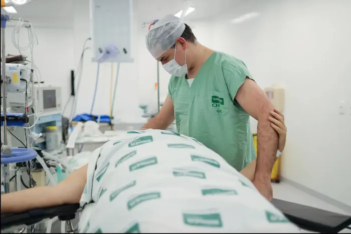 Profissional de saúde acomoda a paciente na mesa do centro cirúrgico