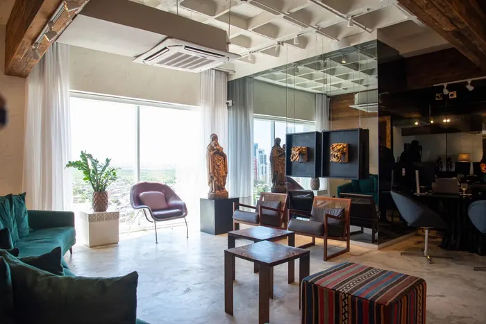 Recepção do Instituto Nogueira, com poltronas, imagens sacras e janelas para a cidade